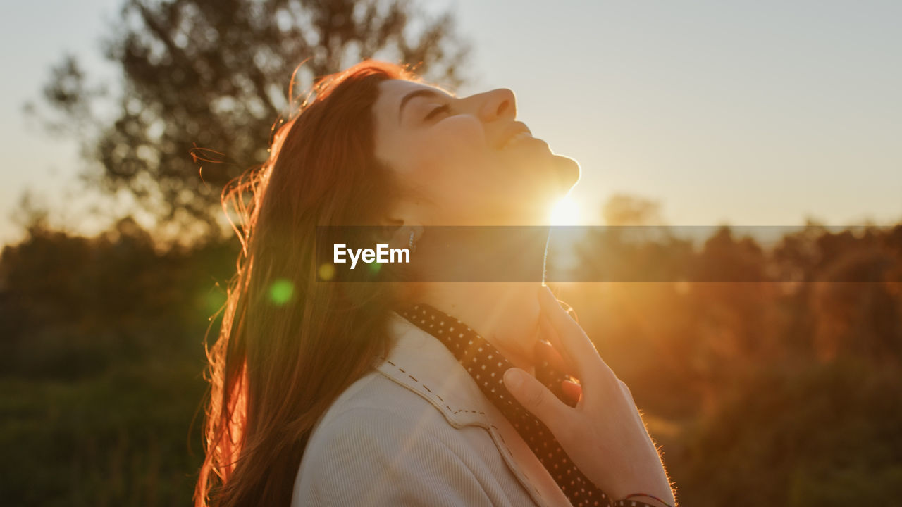 Beautiful girl in the countryside in front of the setting sun