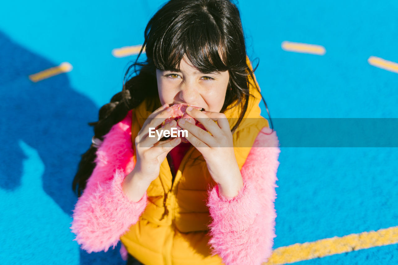 Girl eating donut while sitting on basketball court