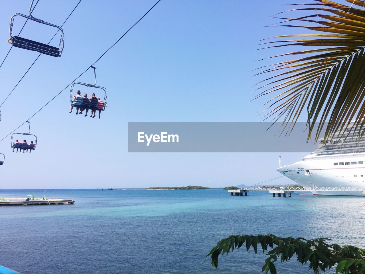 Low angle view of ski lift over sea against clear blue sky