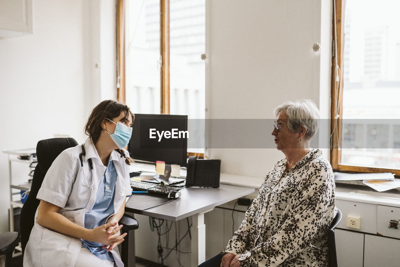 Female doctor consulting senior patient during covid-19