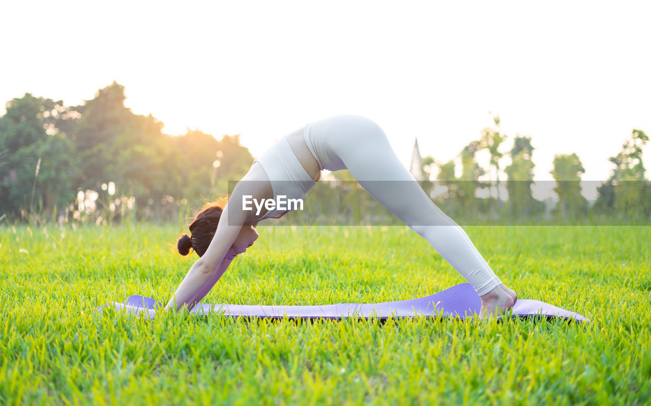 low section of woman doing yoga on field