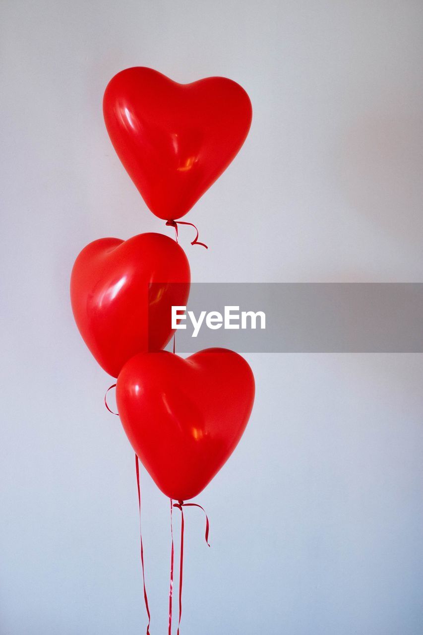Low angle view of red balloons against white background