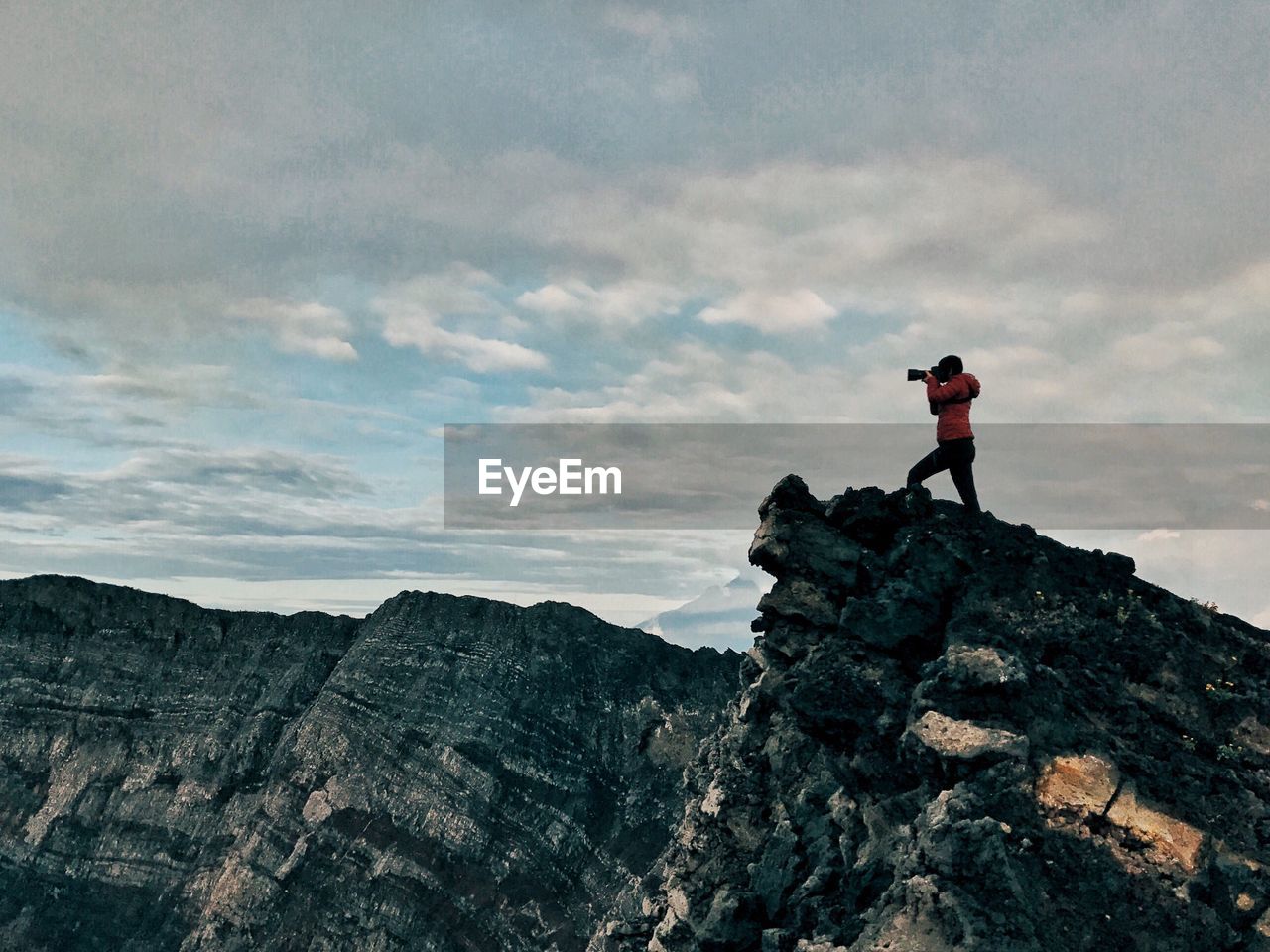 Low angle view of woman standing on mountain against sky