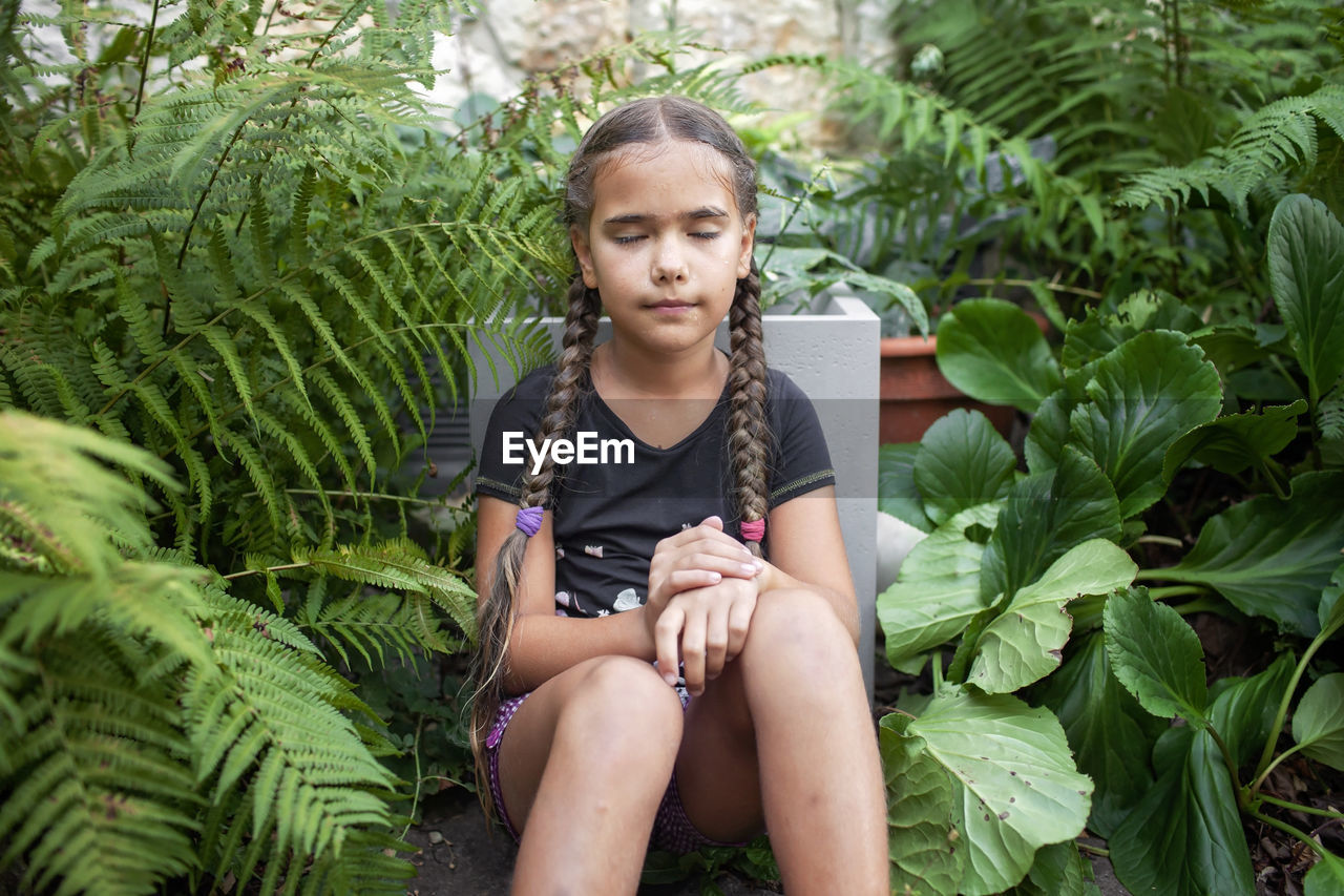 Dreamy girl amidst greenery, embracing summer's tranquil air.