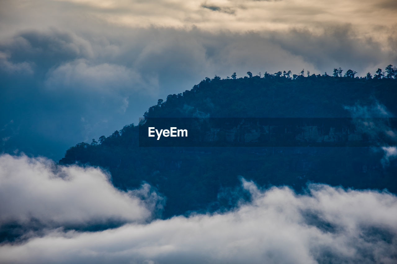 Low angle view of mountains seen through cloud against sky