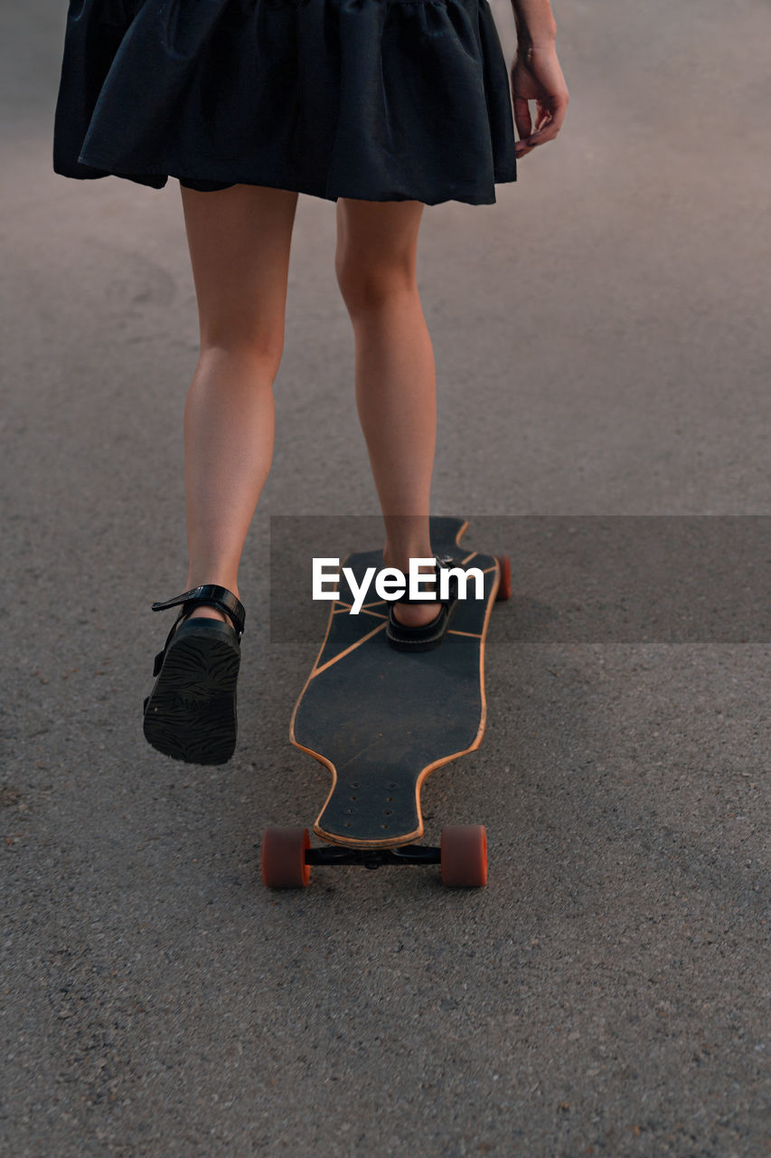 Low section of woman skateboarding in city