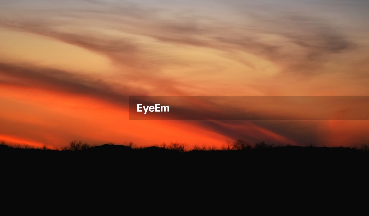 Scenic view of silhouette landscape against orange sky