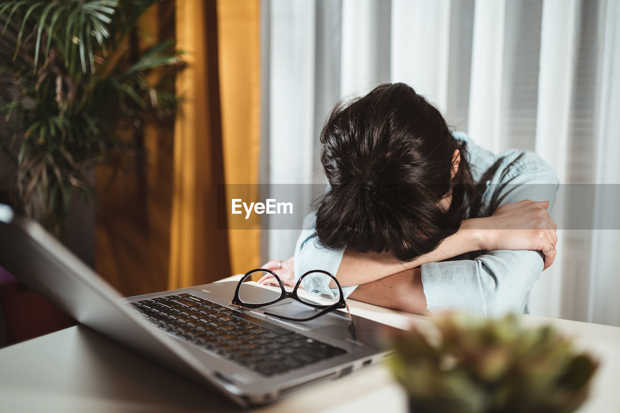 REAR VIEW OF WOMAN USING LAPTOP