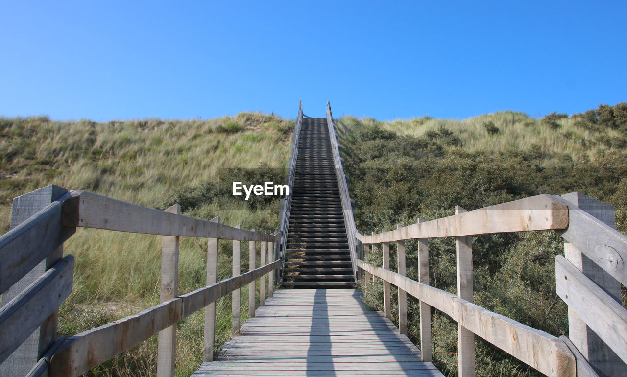 Footbridge at the beach against clear blue sky