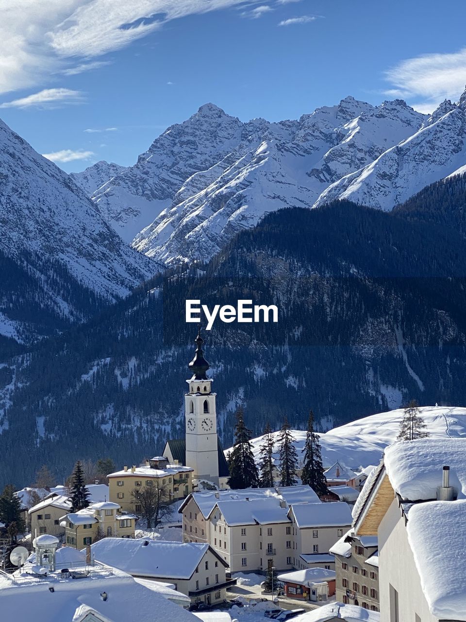 Snow covered houses by mountain against sky