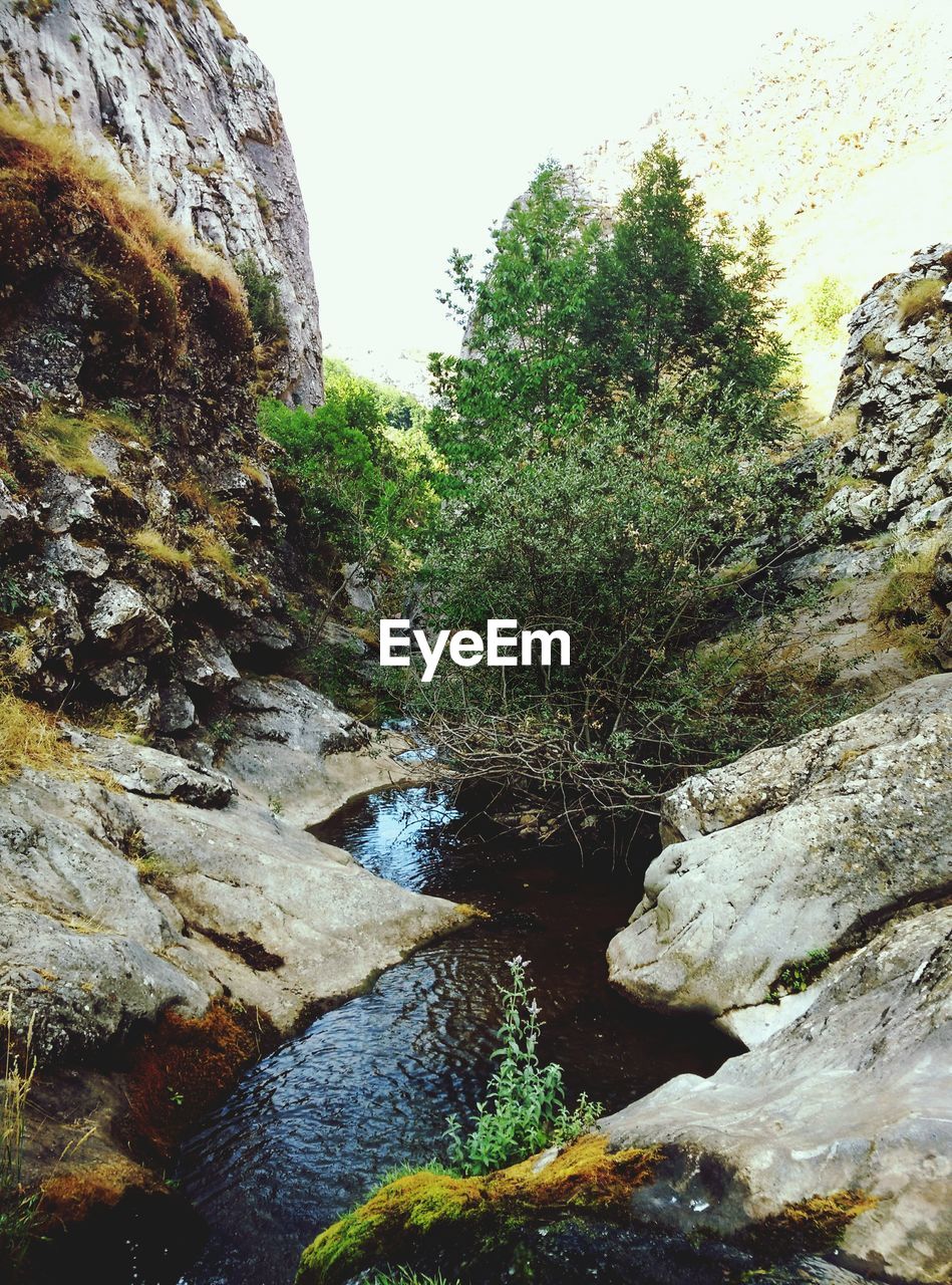 RIVER AMIDST ROCKS AGAINST SKY