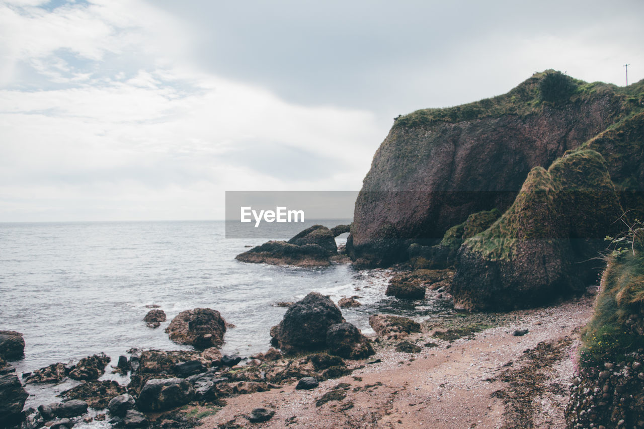 Rock formation on beach against sky