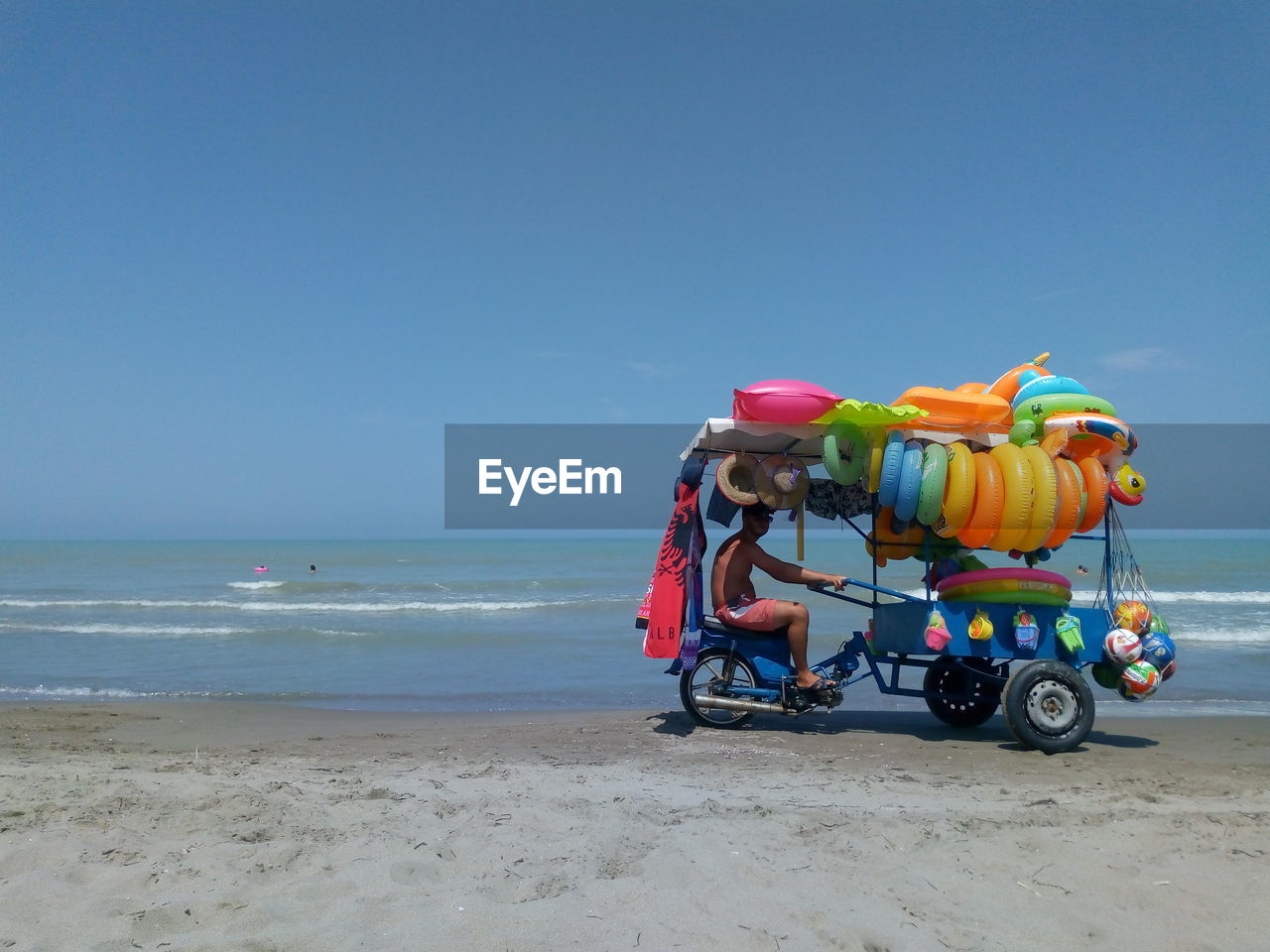 Side view of man selling pool rafts at beach 