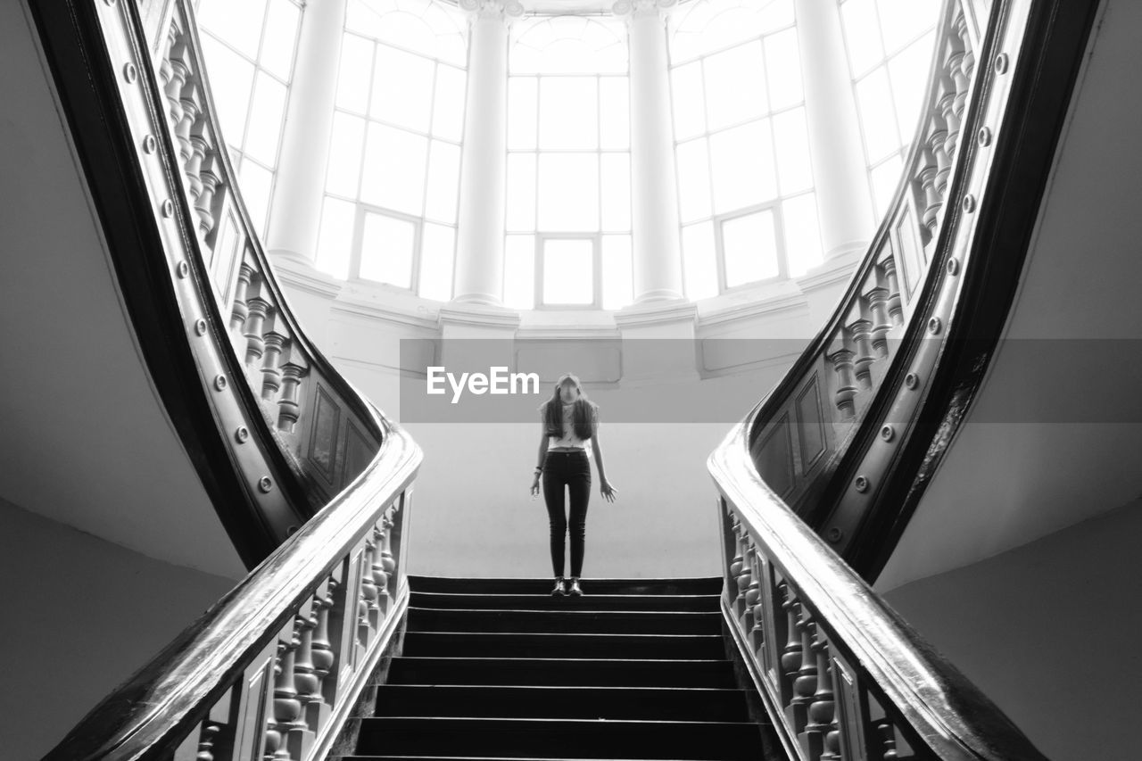 Low angle view of woman standing on staircase in building