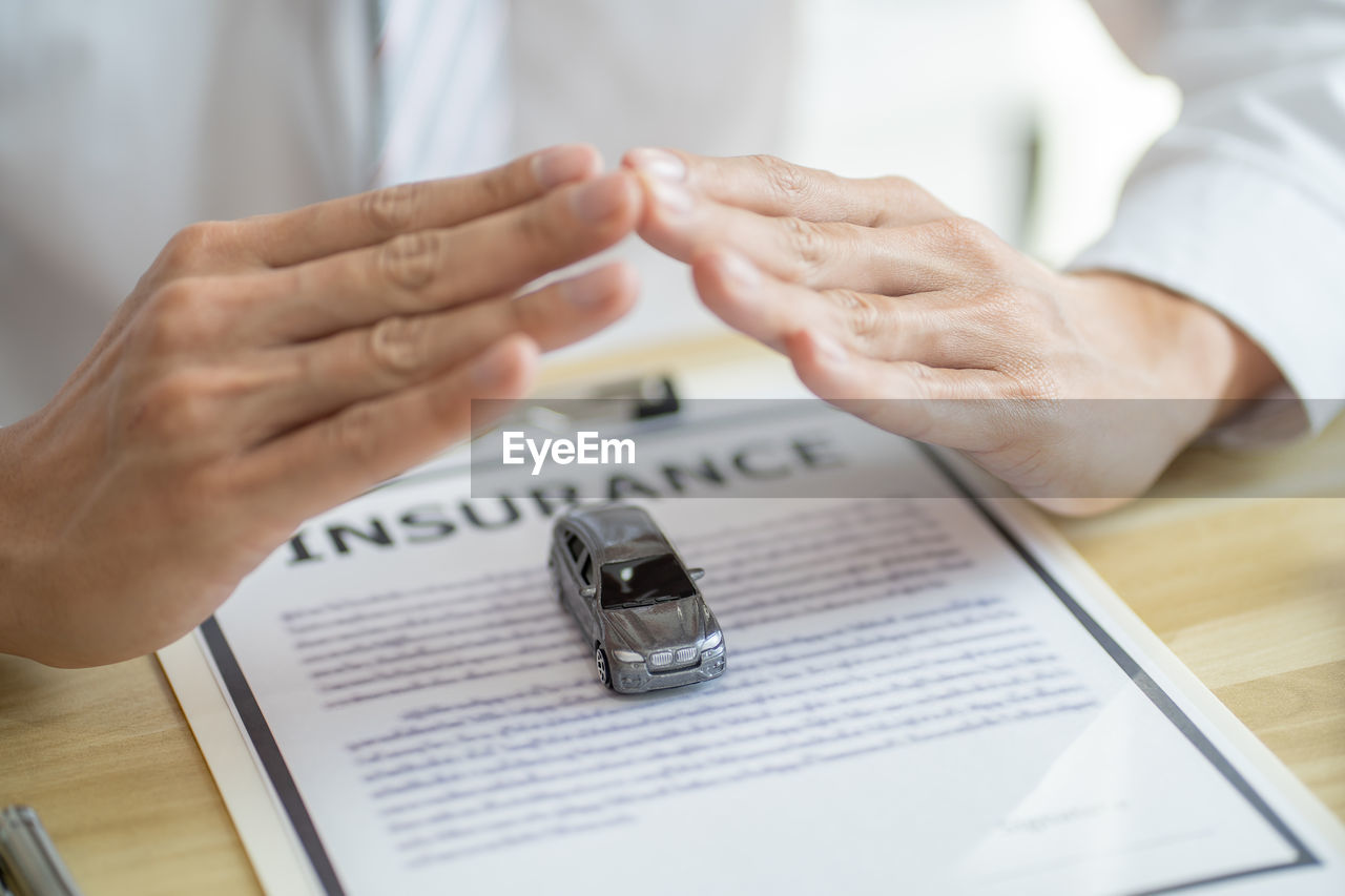 hand, adult, ring, indoors, jewelry, women, business, men, writing, two people, close-up, document, occupation, female, wedding ring, communication, table, holding, selective focus, dedication