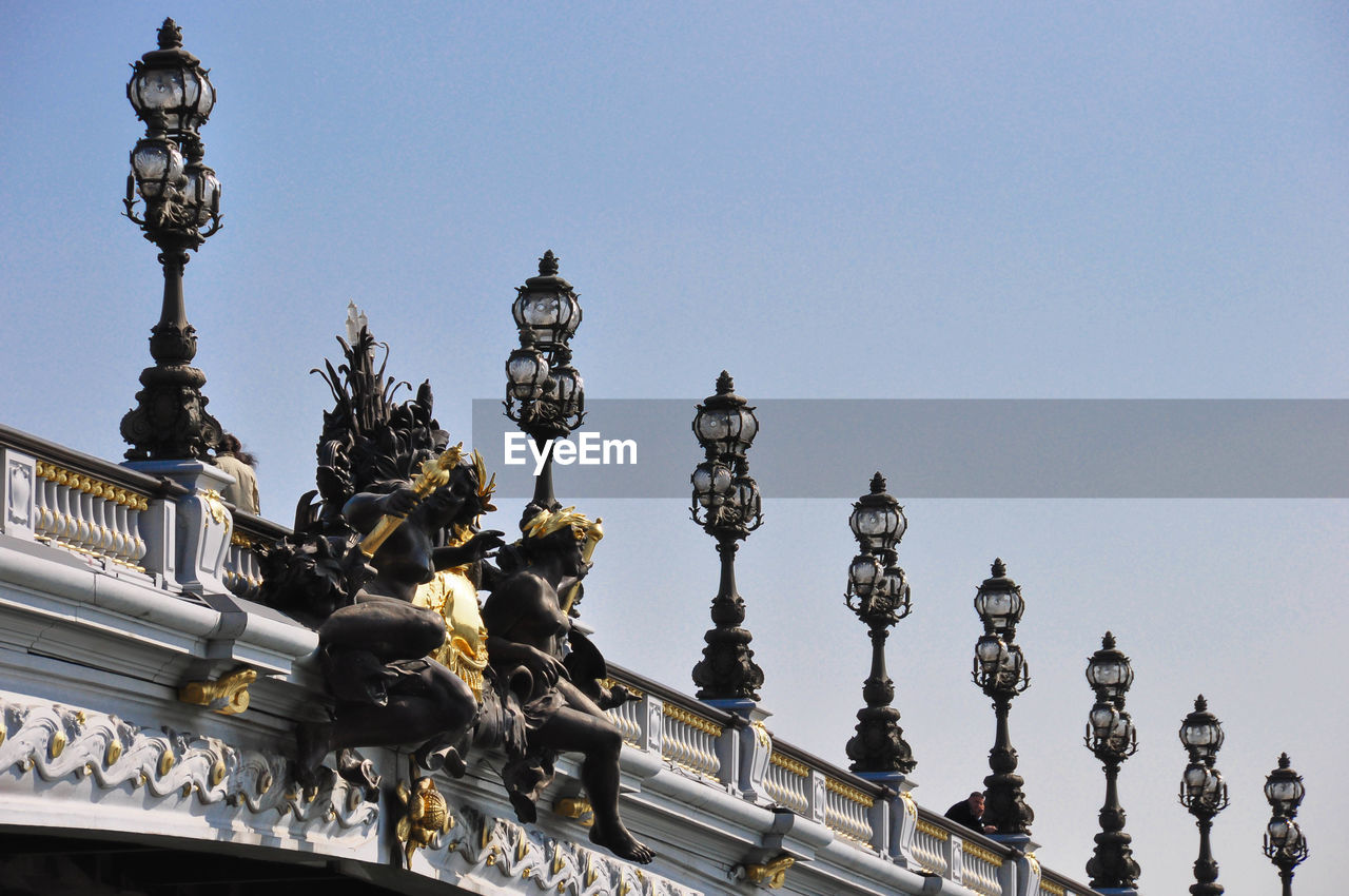 Low angle view of statues on pont alexandre iii against clear sky in city