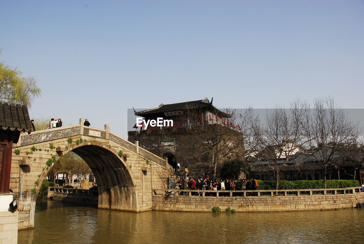 PEOPLE ON BRIDGE OVER RIVER AGAINST SKY