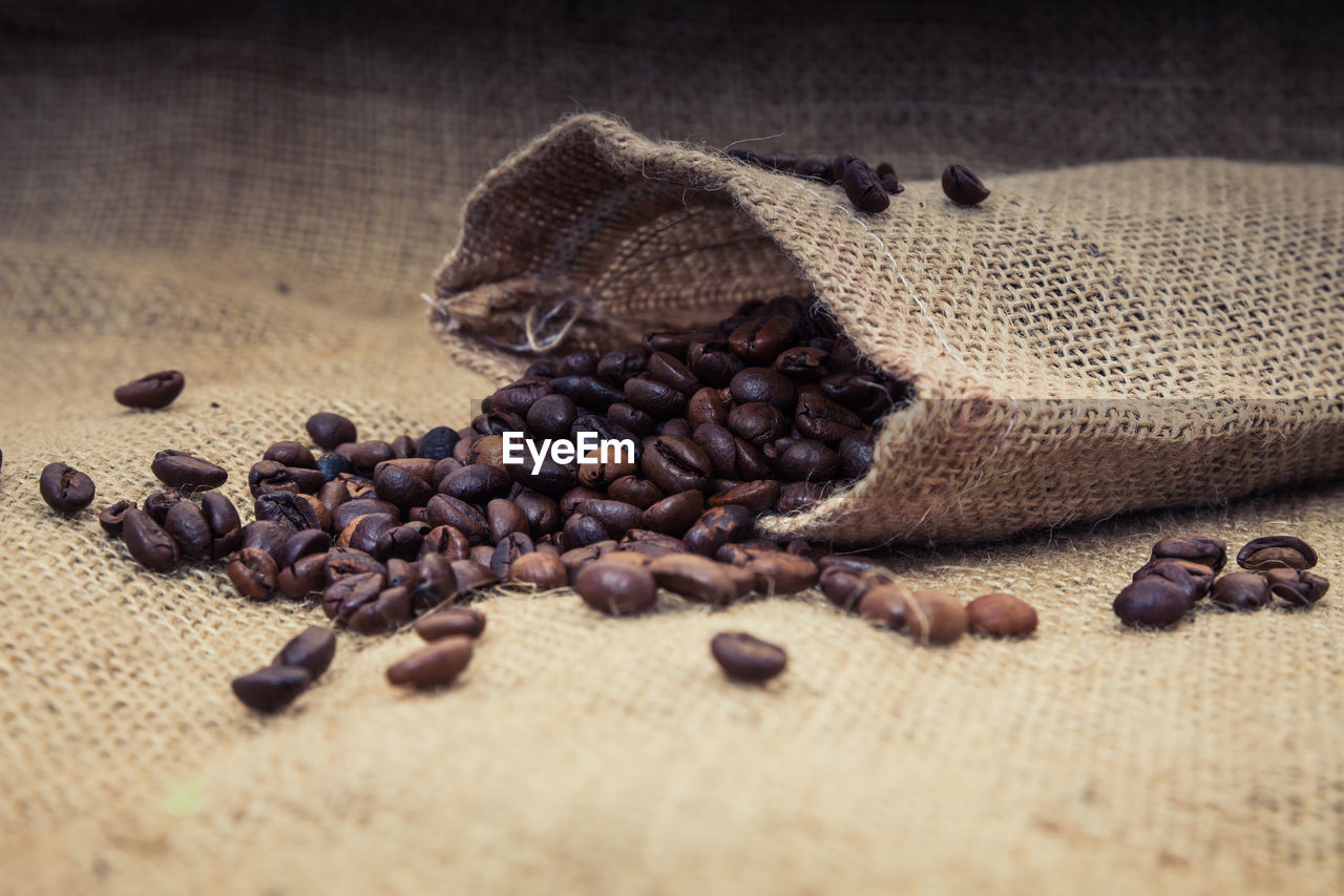 Close-up of roasted coffee beans spilling from burlap