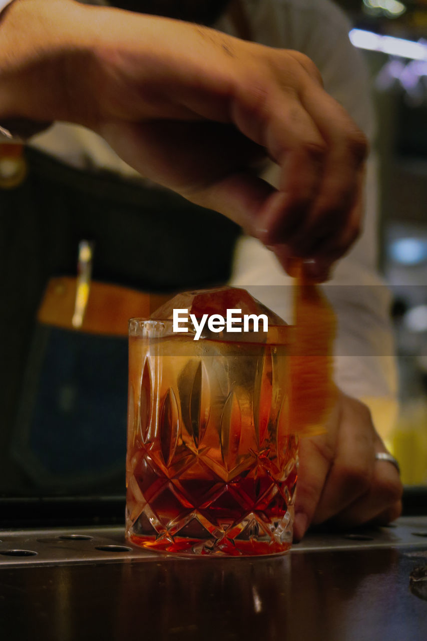 Midsection of man with drink on table in restaurant