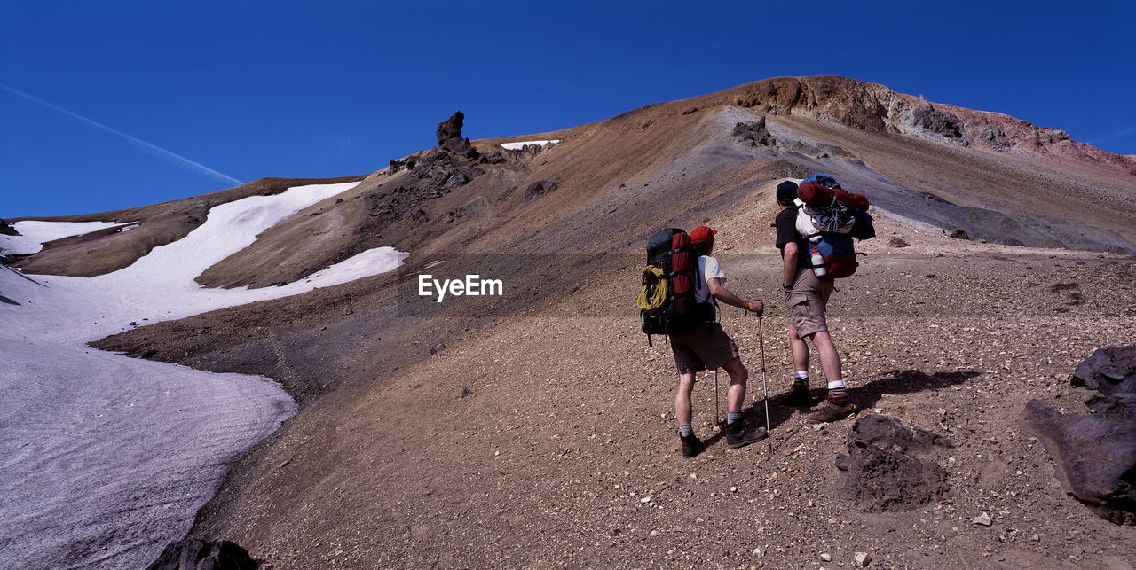 Two hikers hiking up a mountain in landmannalaugar