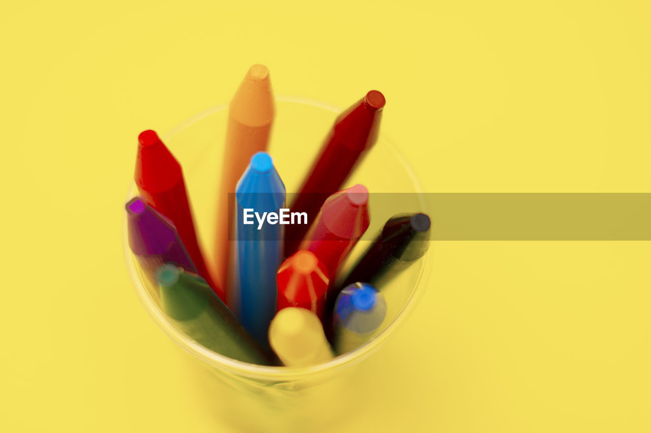High angle view of multi colored crayons on yellow background