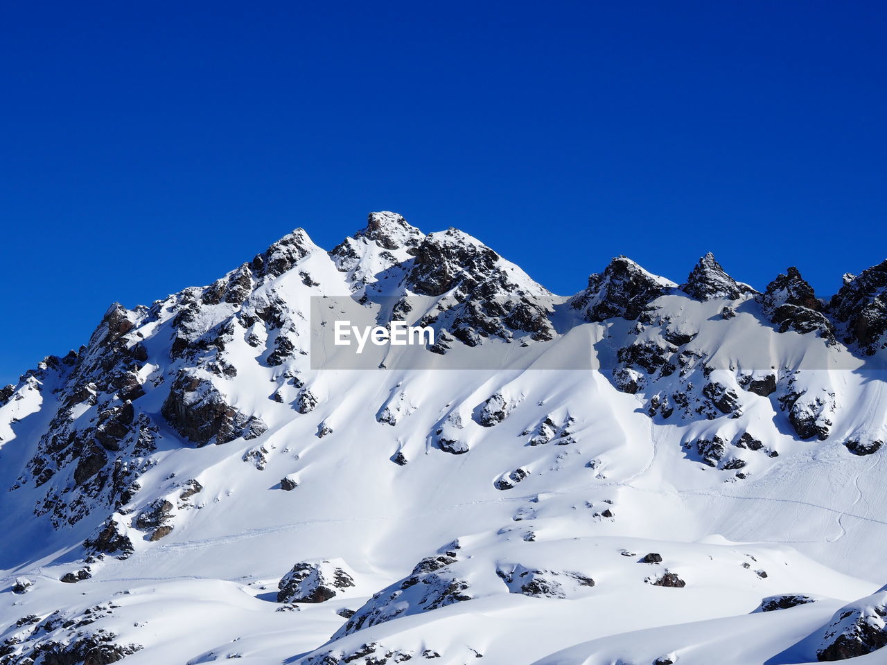 Snowcapped mountain range against clear blue sky