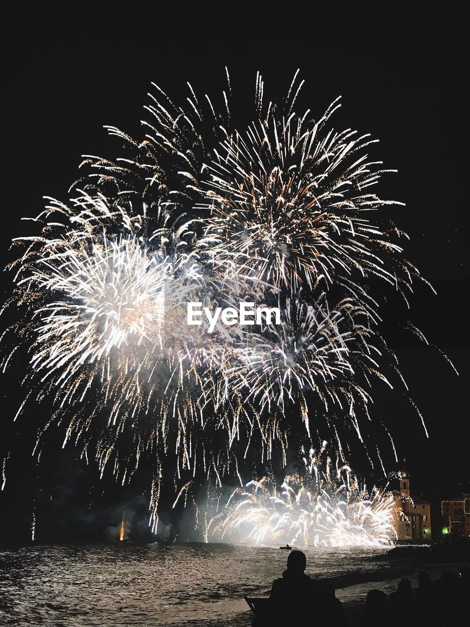 Low angle view of firework display over sea at night