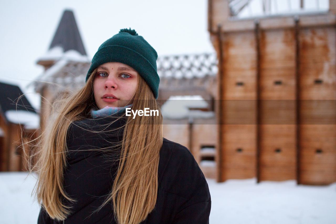 Portrait of young woman with long hair standing outdoors during winter