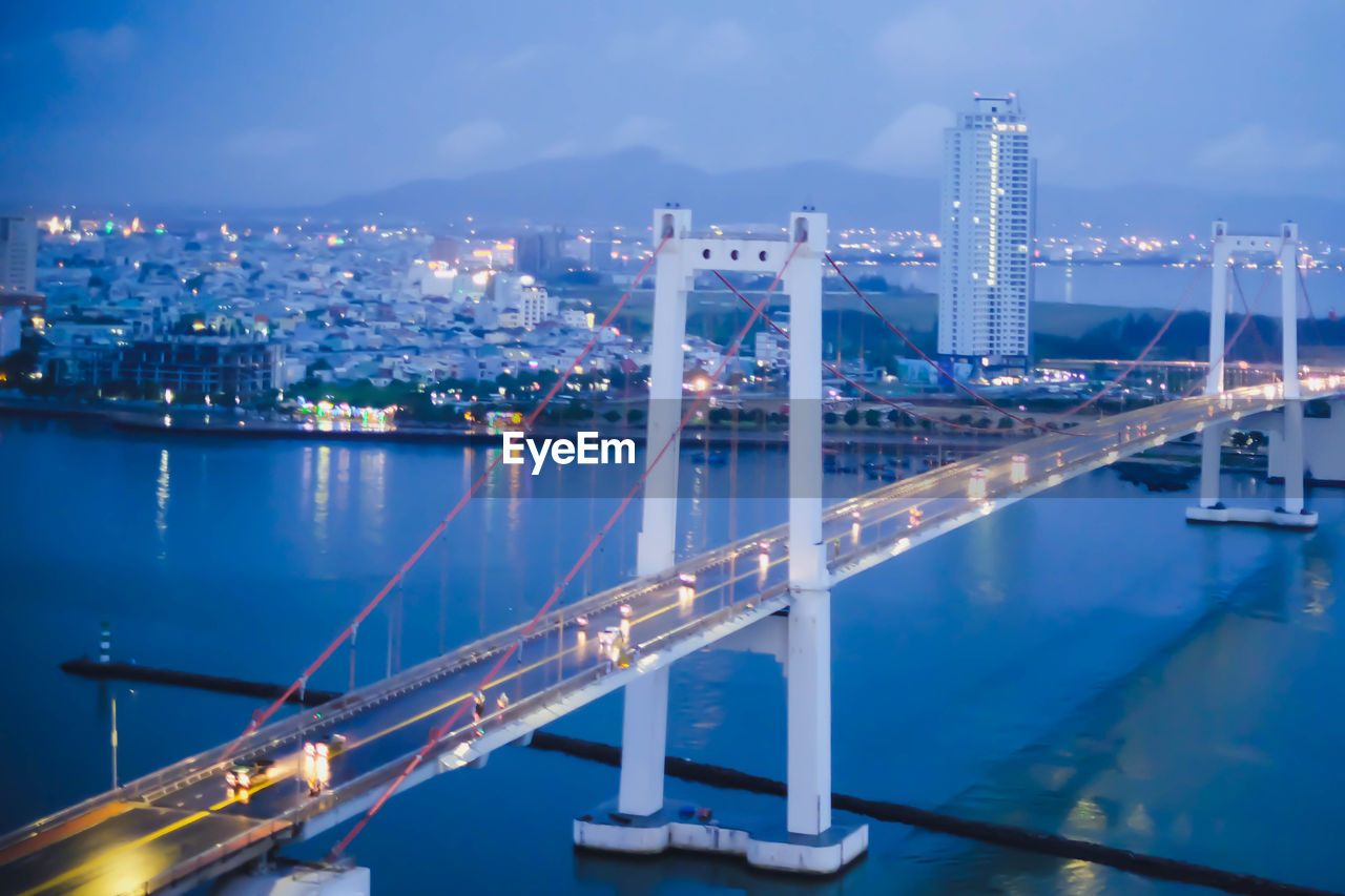 Illuminated bridge over river in city at night