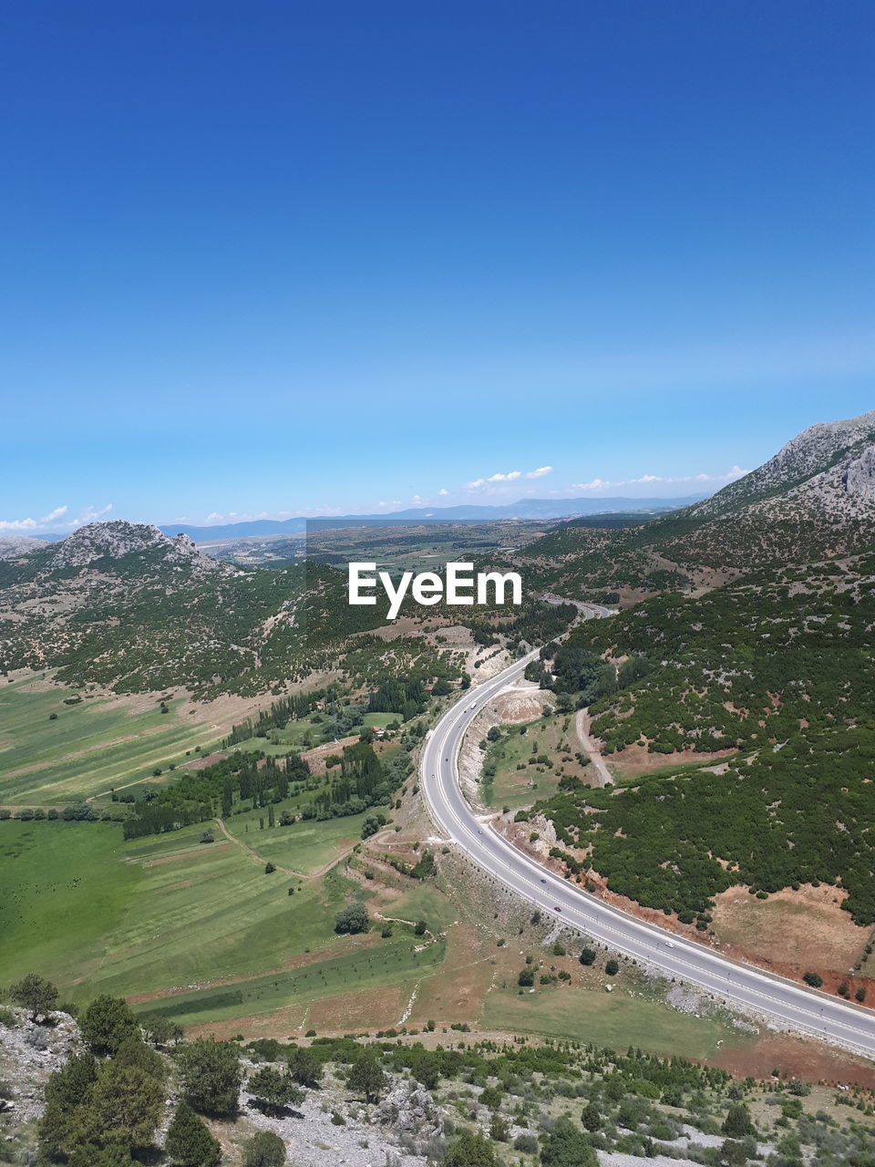 High angle view of road amidst landscape against clear blue sky