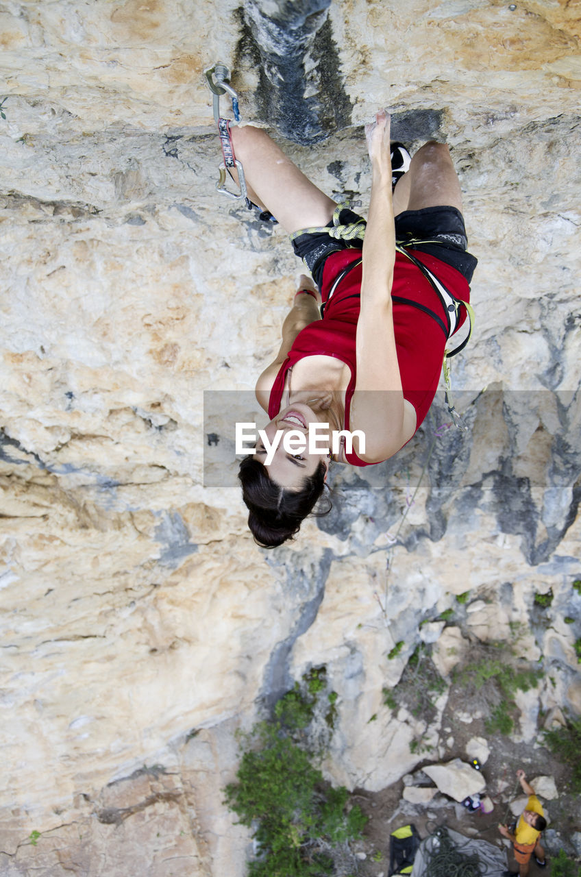 Directly above portrait of smiling young woman climbing rocky mountain