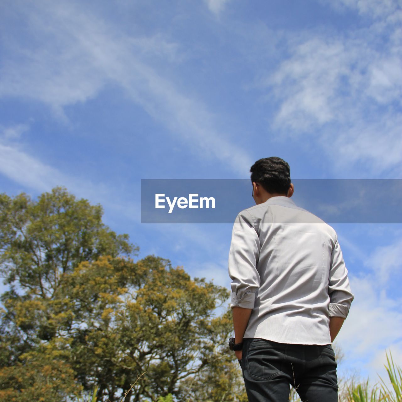 Rear view of man standing against blue sky