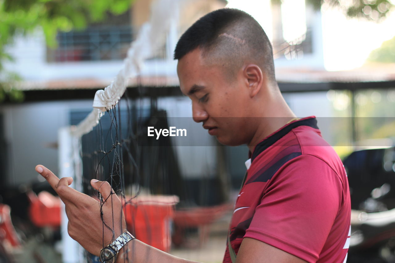 Side view of man standing by sports net