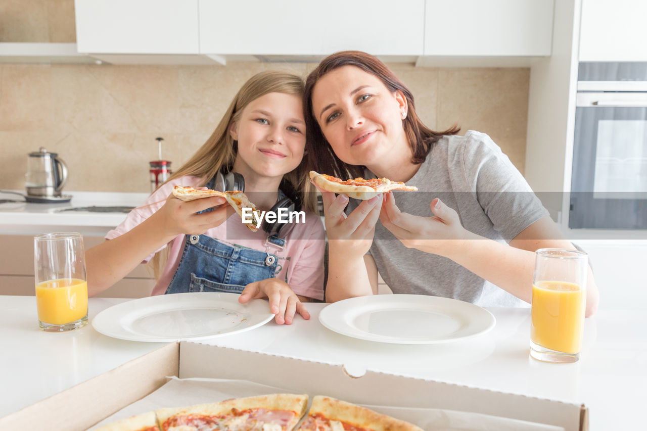 Portrait of mother and daughter eating food at home