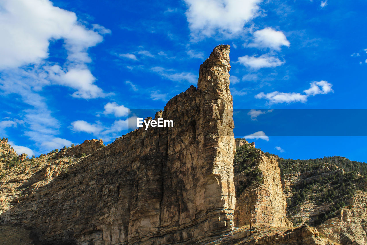 LOW ANGLE VIEW OF ROCK FORMATION AGAINST BLUE SKY
