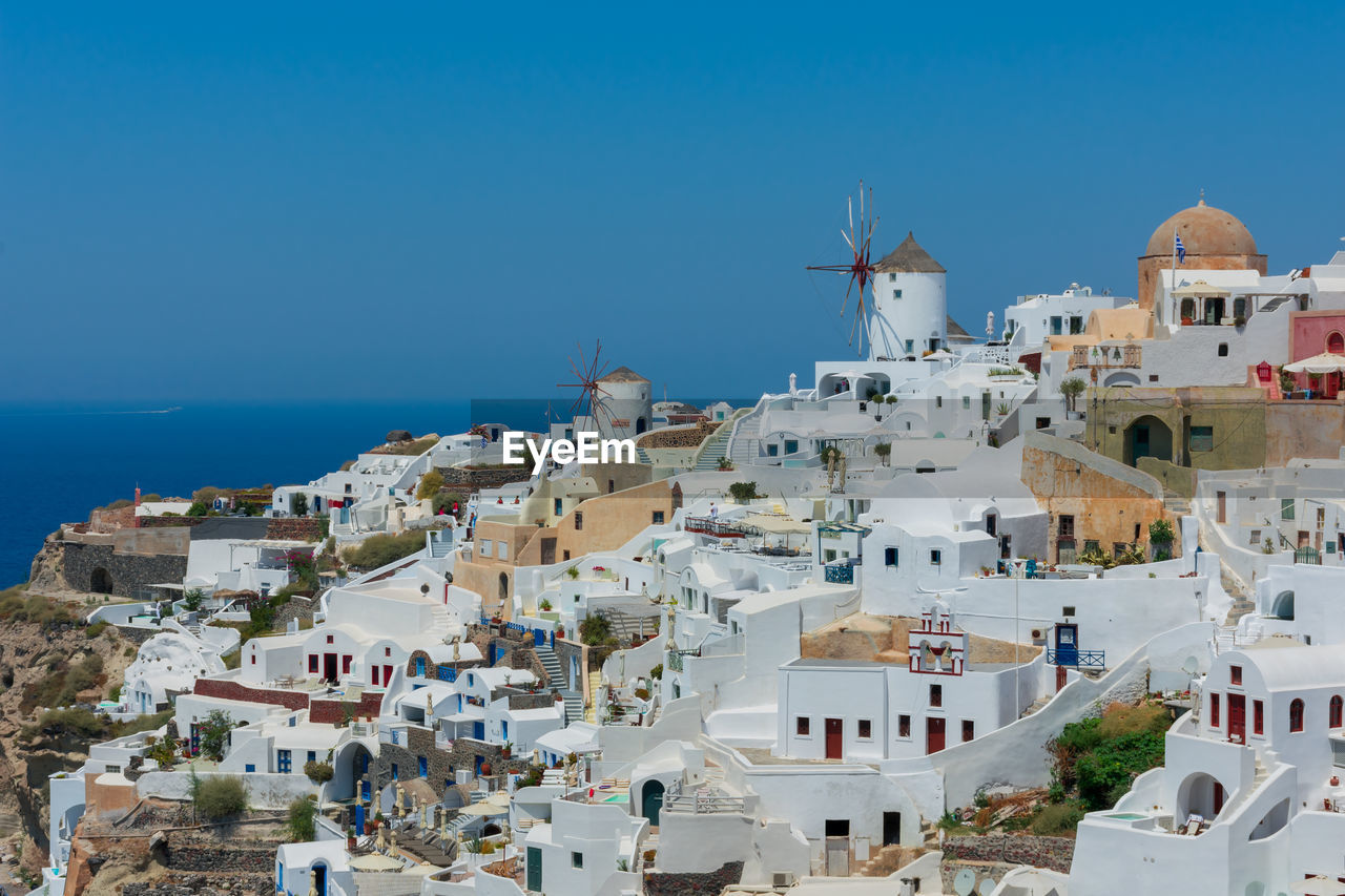 Amazing panoramic view of some white houses of the village of touristic oia in santorini island in aegean sea. the windmill is at the top of the village and the sea at the background. horizon