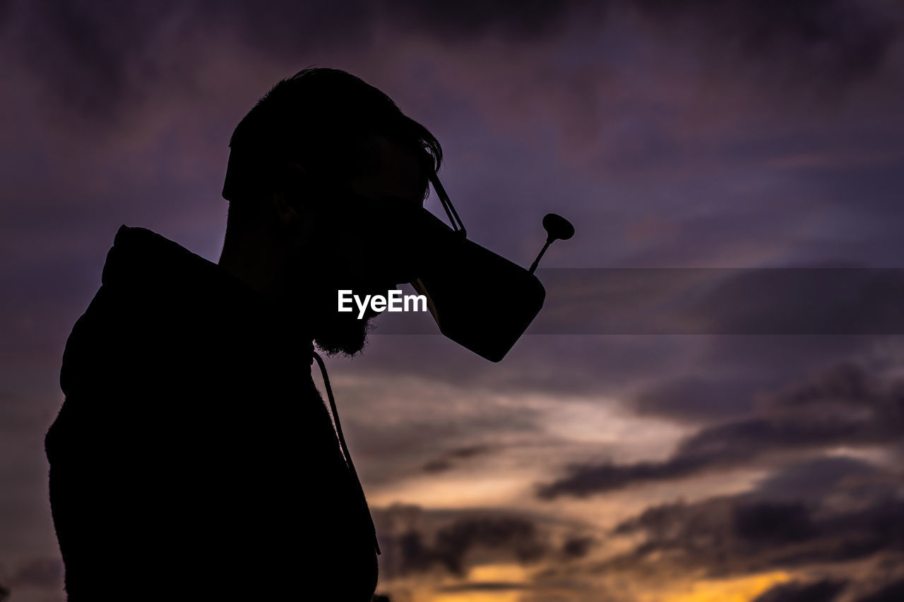 Silhouette man wearing vr goggles against sky