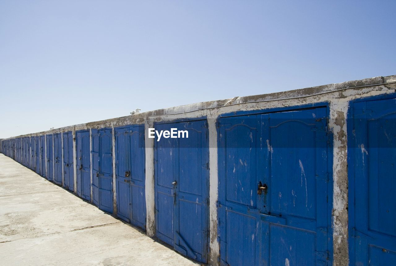 Built structure with closed blue doors against sky