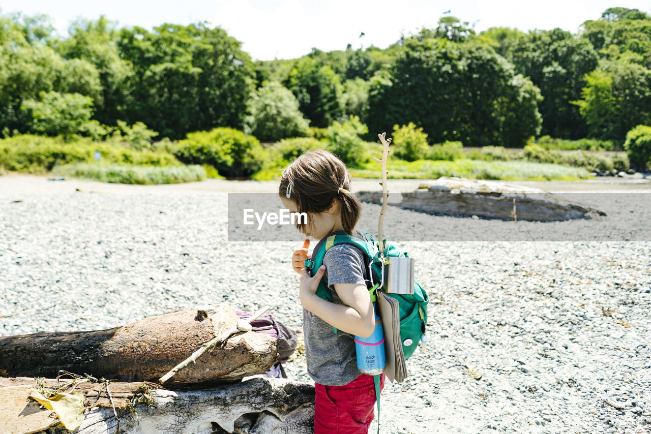 Side view of a young child with an adventure backpack on the beach