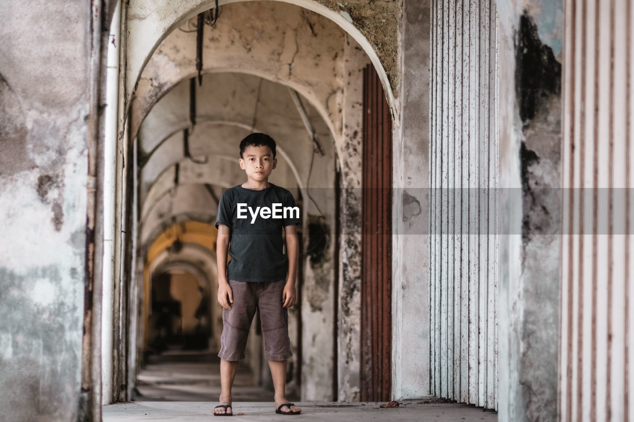 Portrait of boy standing in arch building