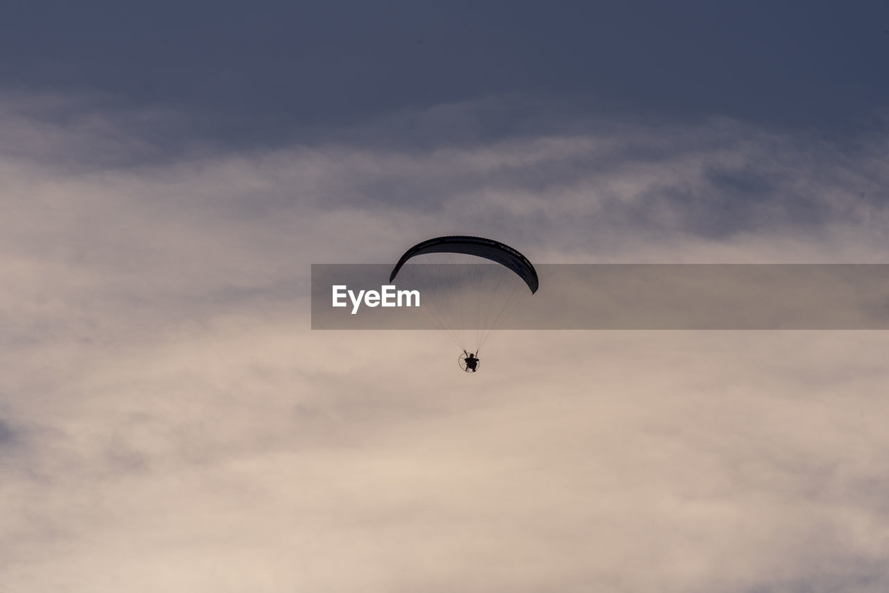 Low angle view of person paragliding against sky