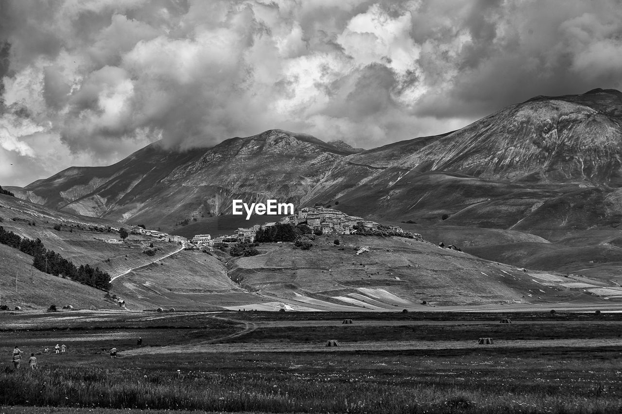 Scenic view of field and mountains against cloudy sky