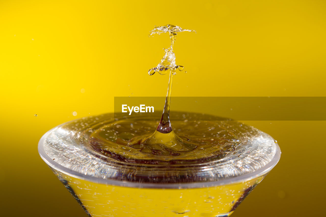 Close-up of water drops on glass against yellow background