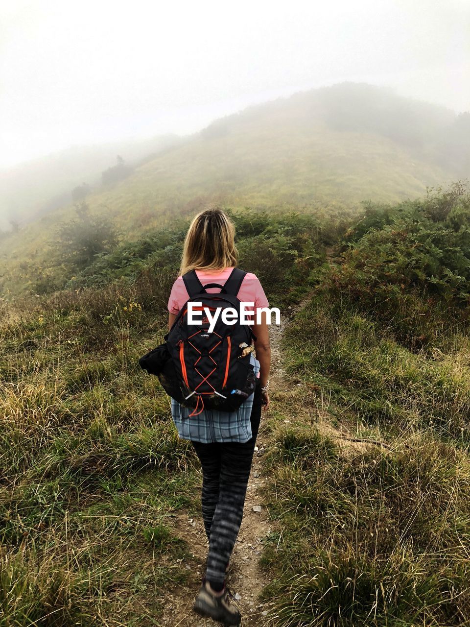 REAR VIEW OF WOMAN STANDING ON LAND AGAINST MOUNTAIN