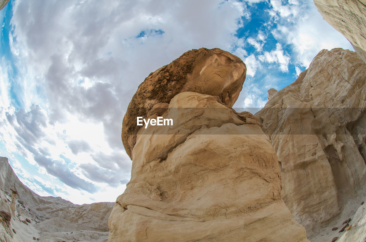 Low angle view of rock formations against cloudy sky