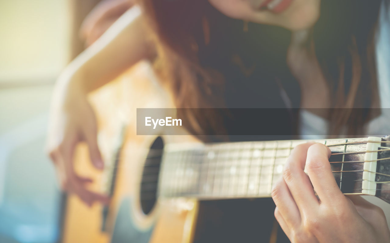 Midsection of woman playing guitar