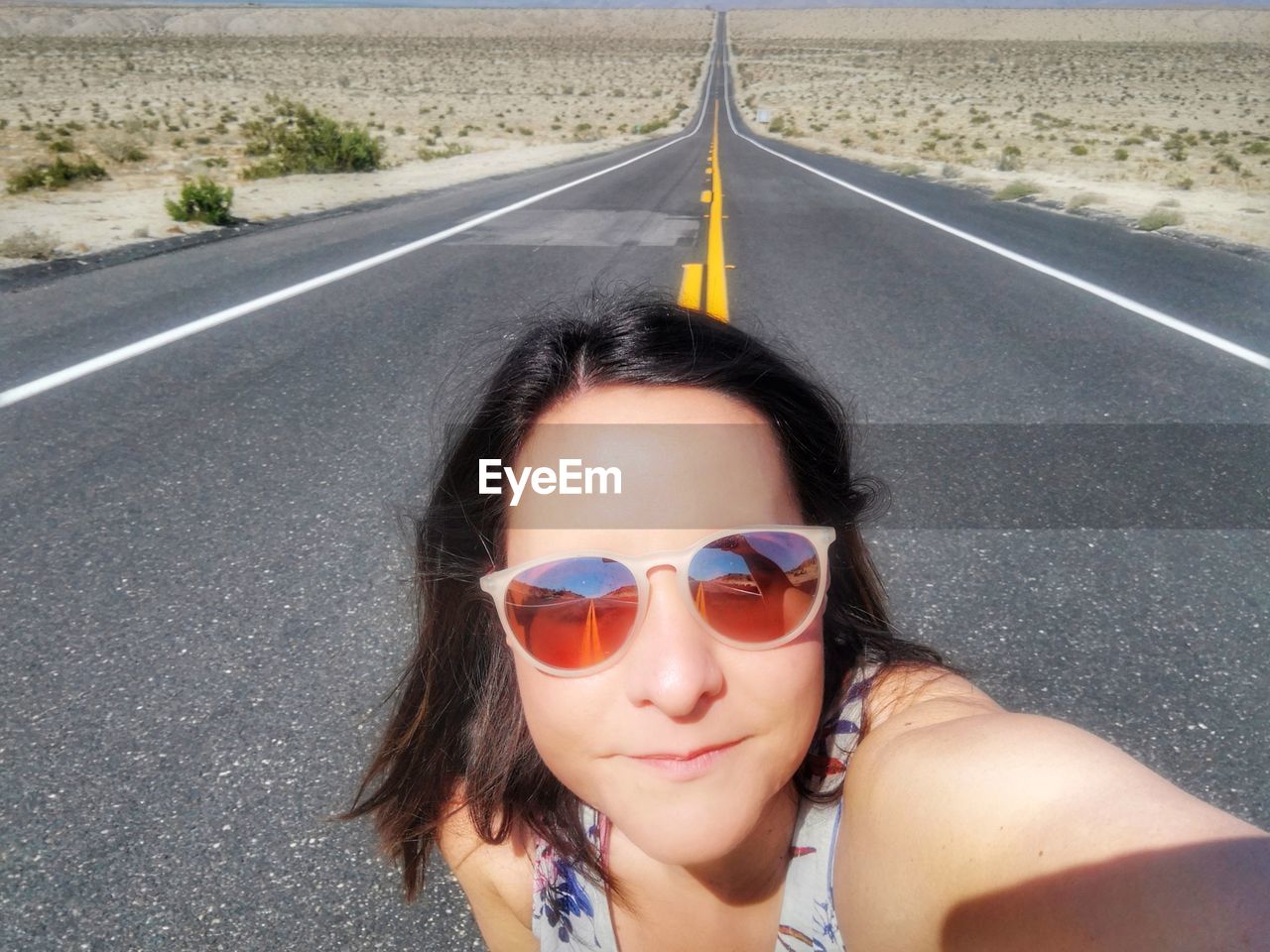 PORTRAIT OF YOUNG WOMAN IN SUNGLASSES AT ROAD