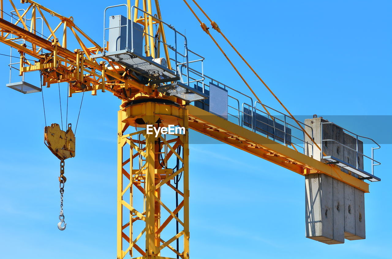 LOW ANGLE VIEW OF CRANE AT CONSTRUCTION SITE AGAINST CLEAR BLUE SKY