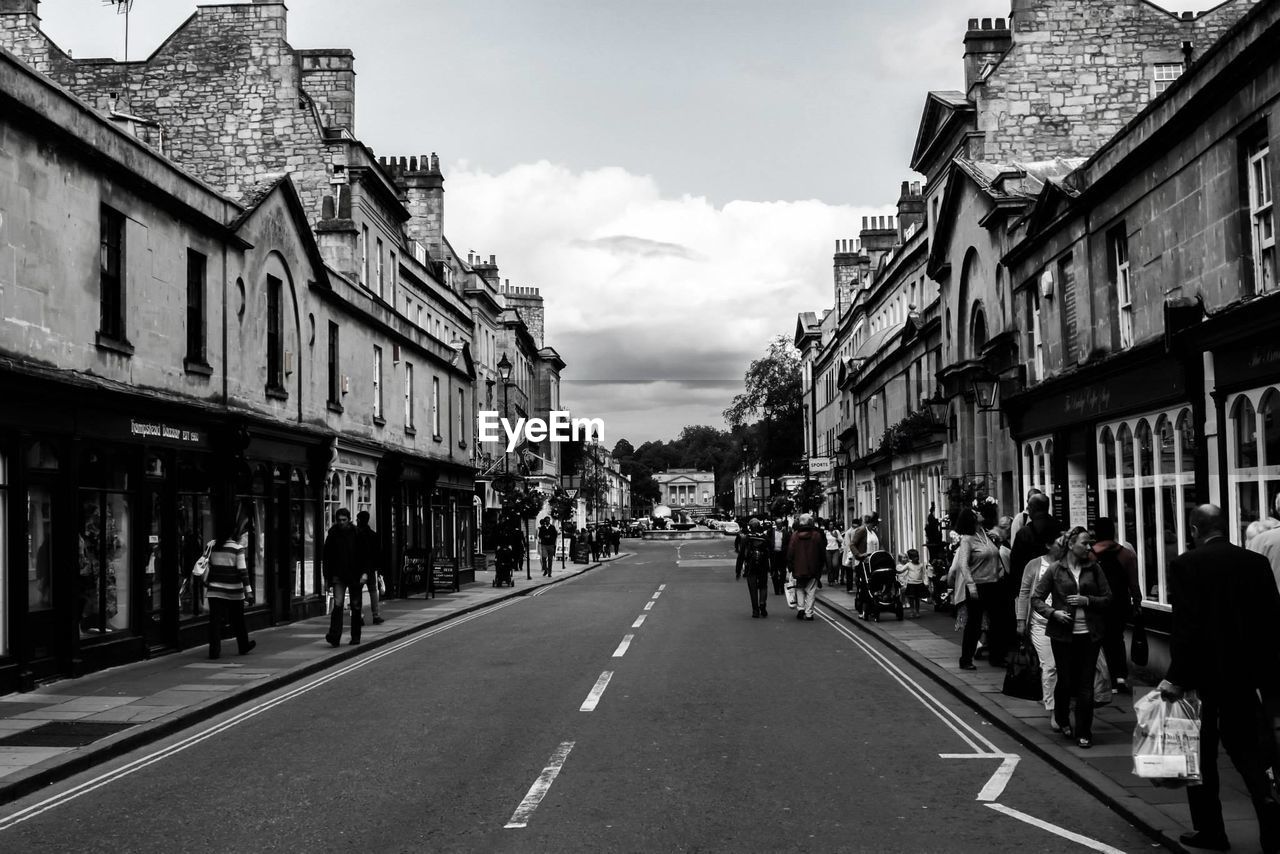 People on city street amidst buildings against sky