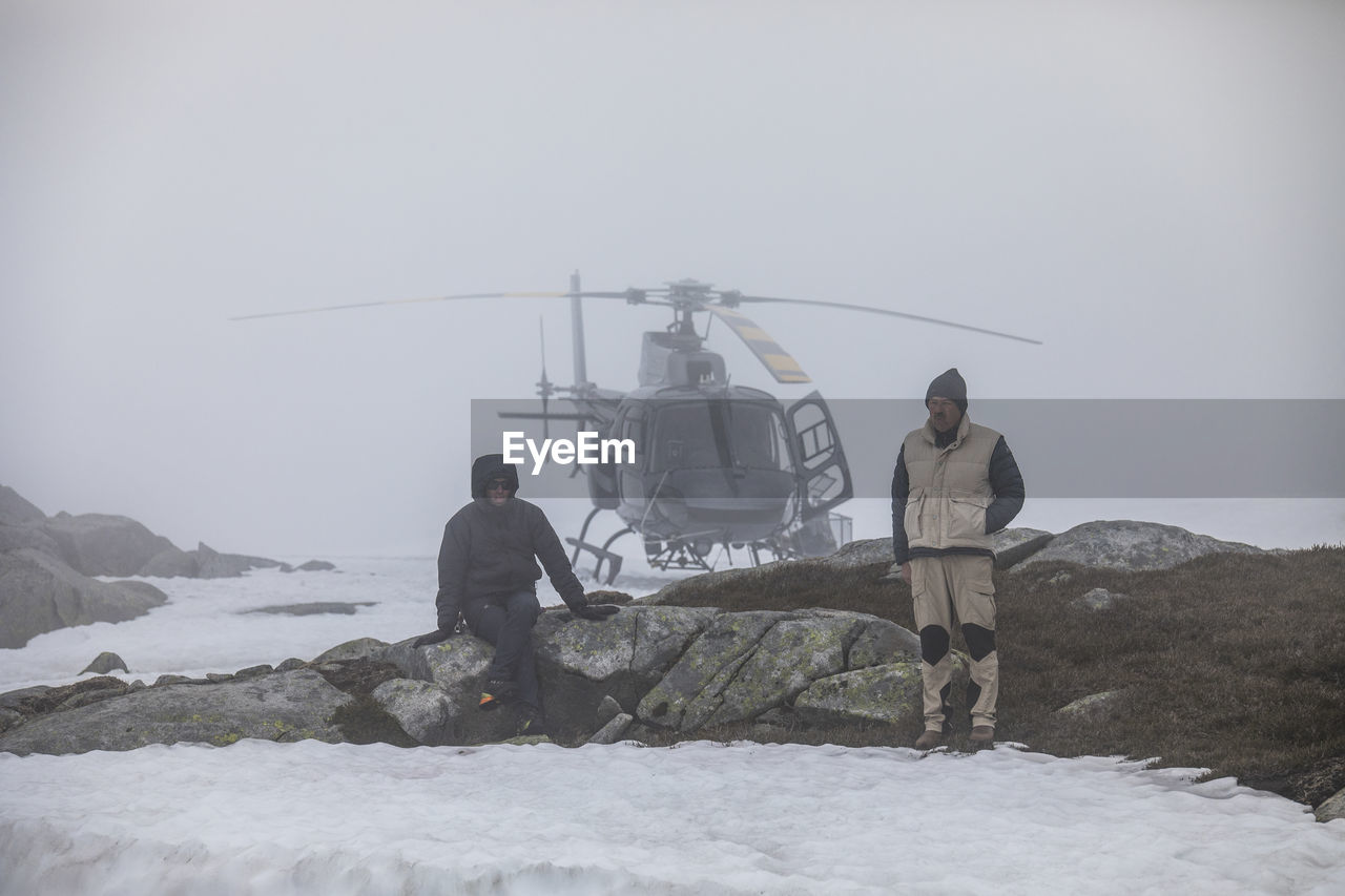 Helicopter pilot and passenger wait for improved weather, stranded.
